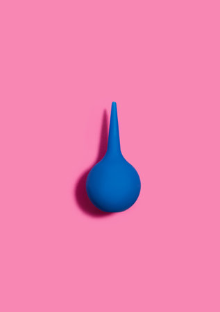 Blue pear-shaped enema on a pink background. Cleansing the body. flat lay.の写真素材