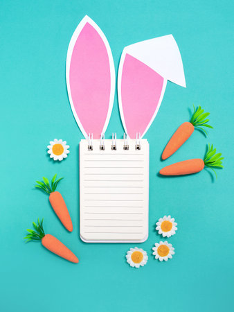 Easter composition. Notepad with place for text with rabbit ears on a green background. Flat lay, top view, copy space.の写真素材