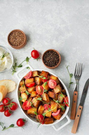 Baked potatoes with fresh tomatoes and microgreens in a ceramic dish on a light background. view from above. copyspace.の写真素材