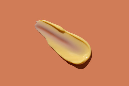 Yellow cosmetic smear of cream texture on a coral background. skincare. copyspace.