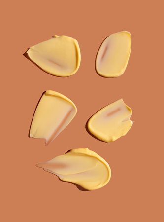 Yellow cosmetic smear of cream texture on a coral background. skincare.の写真素材