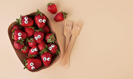 Halloween food. Scared strawberries with eyes in a food container with a fork on a light background. creepy food. Halloween background. view from above. copyspace. Banner.の写真素材