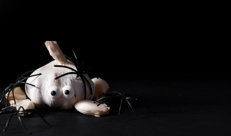 Halloween food. Frightened garlic with eyes and spiders on a dark background. Terrible food. Thematic food. Halloween background. copyspace.の写真素材