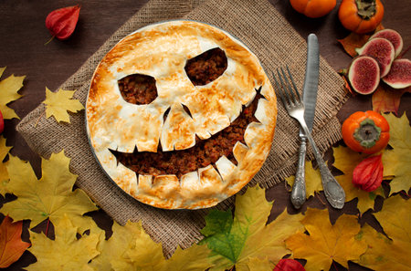 Halloween food. Homemade meat pie with a scary face for Halloween on a wooden tableの写真素材