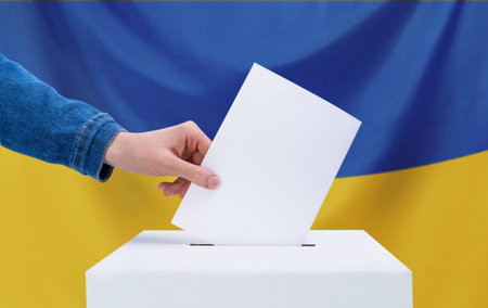 The concept of elections. A human hand throws a ballot into the ballot box. Elections, Ukraine. The...