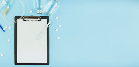 Medicine concept. White paper on a clipboard with pen, stethoscope, dropper system, solution on a blue background. The medicine. Copy space The apartment was lying. Banner.の写真素材
