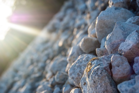 stones under sun rays at dusk on stony beach near seaの写真素材