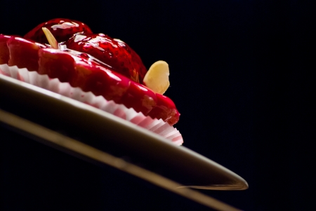 red cupcake on a white plate on wooden matの写真素材