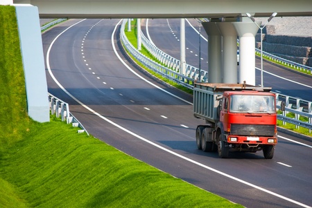 red unloaded truck on the road under bridgeの写真素材