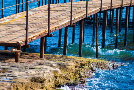 wooden pier on the rocky sea shoreの写真素材