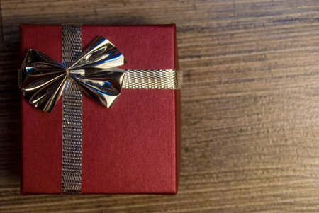 red gift box with ribbon and bow on wood