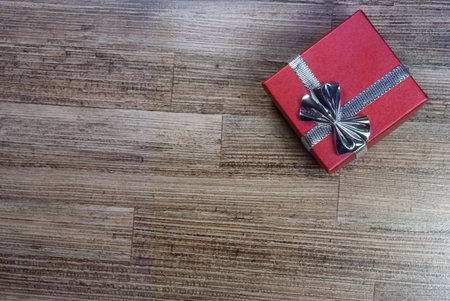 red gift box with ribbon and bow on wood