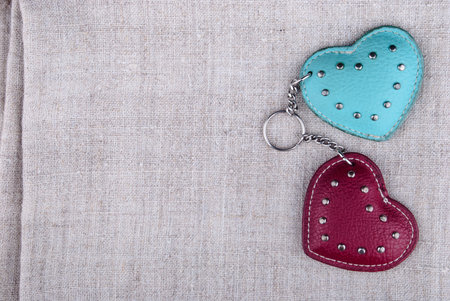 two hearts of leather connected with chain lying on rough textile