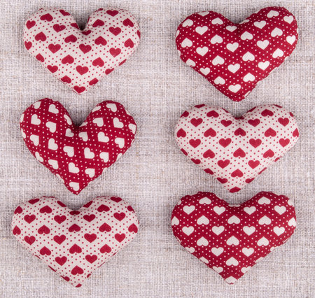 six red hearts on rough textile arranged in two columns