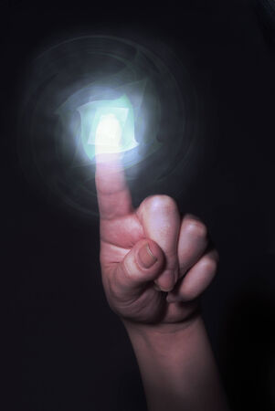 Hand pointing behind shiny circles on black background, as a concept metaphor of technology, science, and business innovationsの写真素材