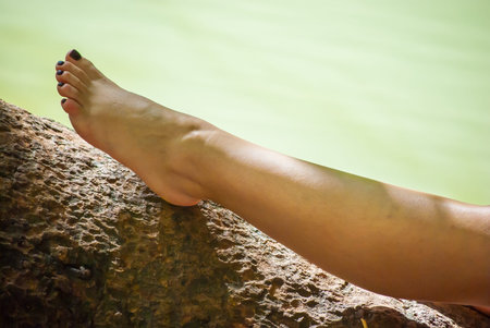 woman's leg on tree near water