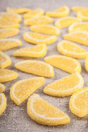 Marmalade pieces in shape of lemon slices on rough textile. Sweet food background.の写真素材