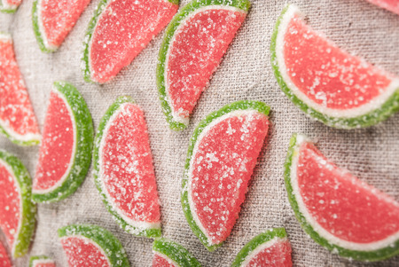 Marmalade pieces in shape of watermelon slices on rough textile. Sweet food background.の写真素材