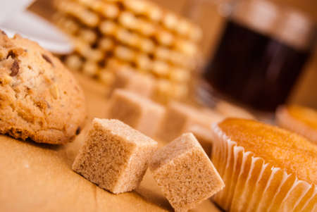 white china cup with brown sugar, cookies, and muffins on tableの写真素材