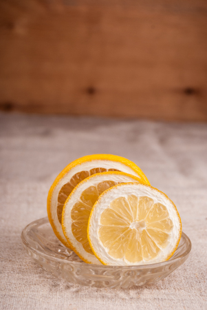 Macro shot of lemon cut to slices on little plate on table covered with rough textileの写真素材
