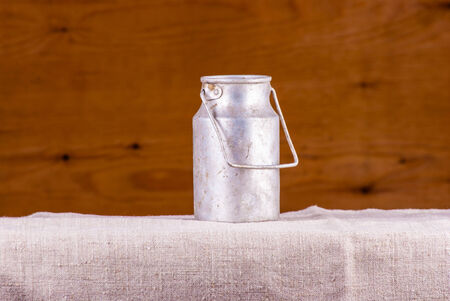 vintage drum for milk on burlap against woodの写真素材