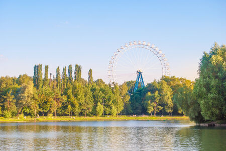 Landscape with ferris wheel, pond and green parkの写真素材