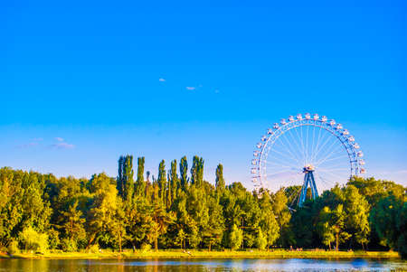 Landscape with ferris wheel, pond and green parkの写真素材