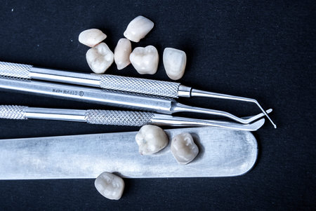 close up dental instruments and false teeth on black background