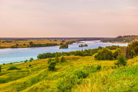 Sunset in countryside. Colorful landscape with trees, hills, river and cloudscapeの写真素材