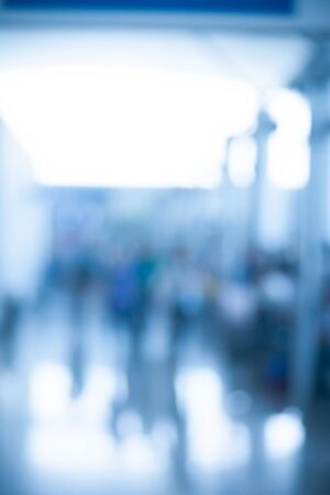 Blurred photo of an airport terminal with unrecognizible passengers passing by with luggage. Blurred background for topics of travel and transportation.の写真素材