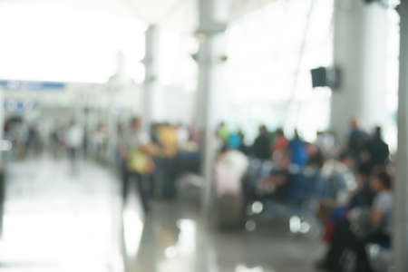 Blurred photo of an airport terminal with unrecognizable passengers passing by with luggage. の写真素材