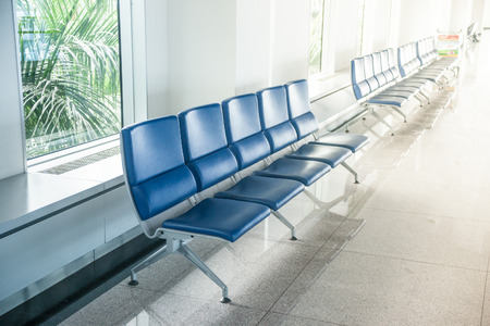 Airport waiting area with rows of blue seats. Background for topics of travel and business.の写真素材
