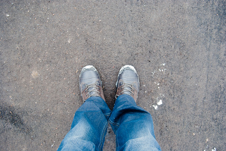 Male sneakers with snow on the asphalt road in early springの写真素材