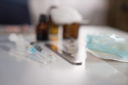 Syringe with glass vials and medications pills with defocused doctors hands preparing for a treatment procedureの写真素材