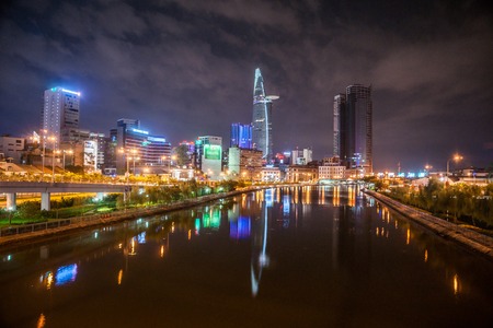 Cityscape of Ho Chi Minh at night with bright illumination of modern architecture, viewed over Saigon river in Southern Vietnam.のeditorial素材
