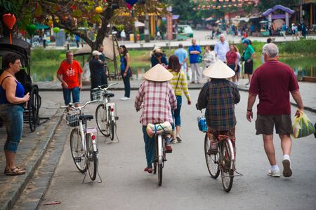 HOI AN, VIET NAM - FEBRUARY 8, 2015: Unidentified tourists and vietnam citizens on bycicles are on a decorated street of Hoi An ancient city, Da Nang province, Vietnam. Hoi An is recognized as a World Heritage Site by UNESCO.のeditorial素材