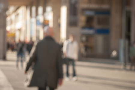 People walking down the street in the evening, beautiful light at sunset. The photo is purposely made out of focus, no faces are recognisibleの写真素材