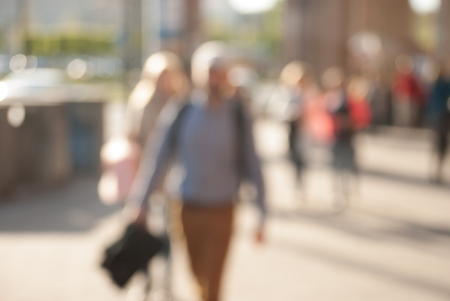 People walking down the street in the evening, beautiful light at sunset. The photo is purposely made out of focus, no faces are recognisibleの写真素材