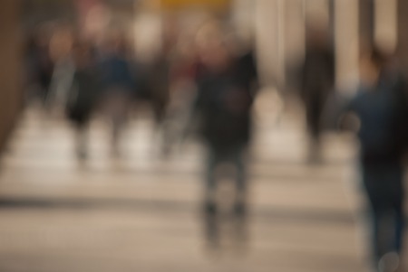 People walking down the street in the evening, beautiful light at sunset. The photo is purposely made out of focus, no faces are recognisibleの写真素材