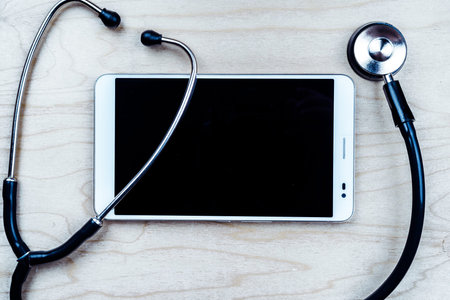 Stethoscope with a tablet computer on wooden table. Medical background