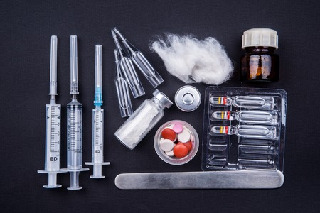 Medical objects still life seen from above on dark background. Syringes with pills and ampulsの写真素材