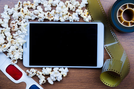 Tablet pc on wood with attributes of cinema. Visual metaphor for content consumption - films and...