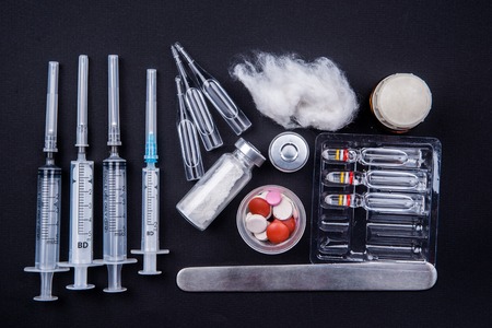 Medical objects still life seen from above on dark background. Syringes with pills and ampulsの写真素材