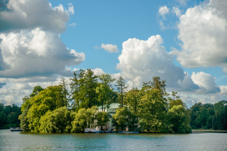Beautiful russian landscape with willows near water of a lake and clouds in blue sky. Catherine park in Pushkin - Tsarskoe Selo, St.Petersburg, Russia.の写真素材