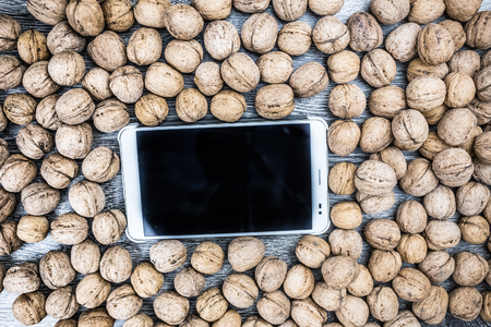 Plenty of walnuts on wood with tablet pc in centre. Image of healthy food and technology. Raw food texture. Rural texture and technological background.の写真素材