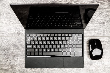 Black laptop on wood viewed from above.の写真素材