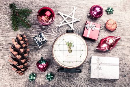 Clock showing almost New Year with christmas fir tree with cones and christmas tree decoration on a wooden background. Template for banner or bavkground, or image for a blog.の写真素材