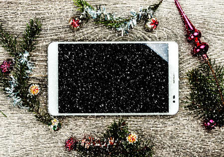 Tablet pc with blank screen and christmas fir tree with cones and christmas tree decoration on a wooden background. Template for banner or bavkground, or image for a blog.の写真素材