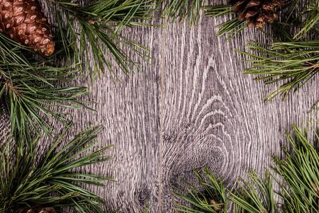 Christmas fir tree with cones on a wooden background, selective focus and place for text. Tonedの写真素材