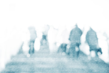 Winter city commuters with snow. Blurred image of people walking on the street. back home after work. Defocused figures of people with snowing effect and frost.の写真素材